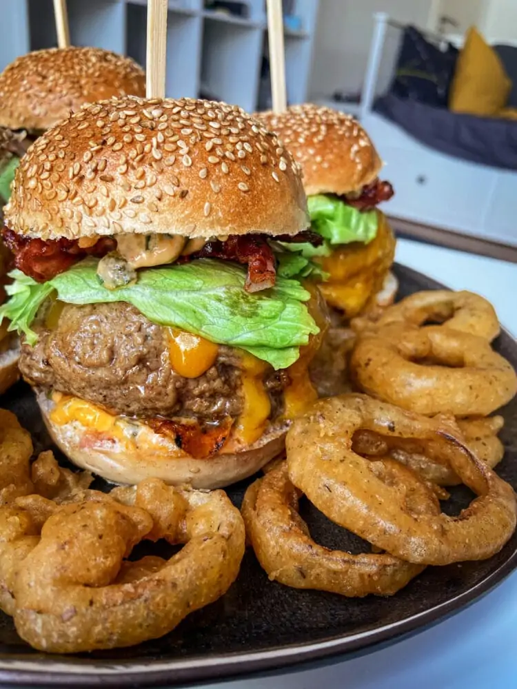 burger de taille imposante avec des onion rings disposés devant