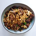 nouilles au boeuf et poivre dans un bol sur fond blanc