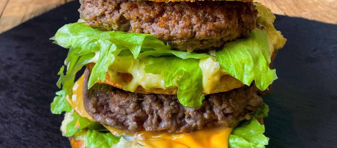 Big Mac maison coupé en deux, avec sa sauce qui déborde