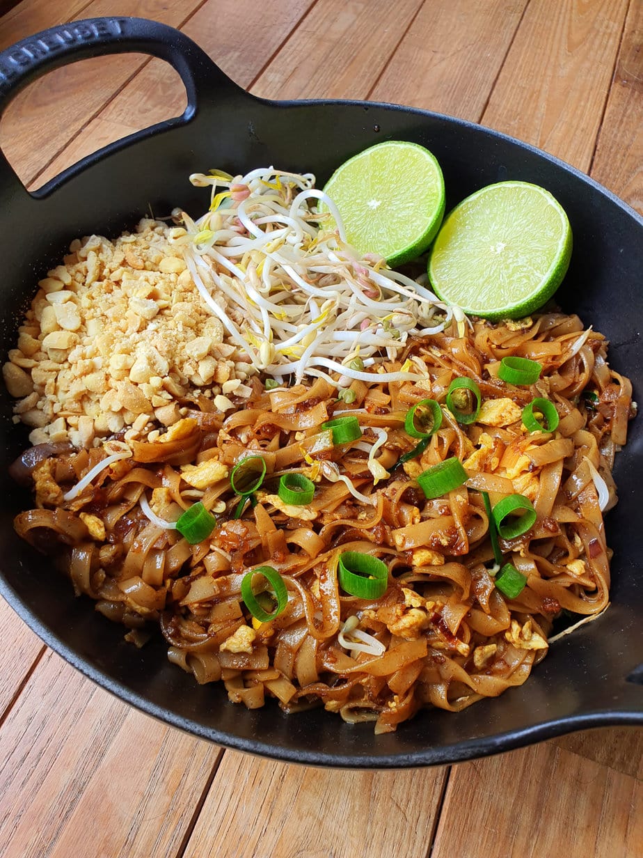 pad thaï dans un wok en fonte sur fond de bois