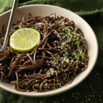 nouilles soba froides au sésame dans une assiette blanche sur fond sombre