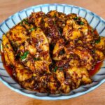 poulet épicé chinois dans une assiette sur fond de bois