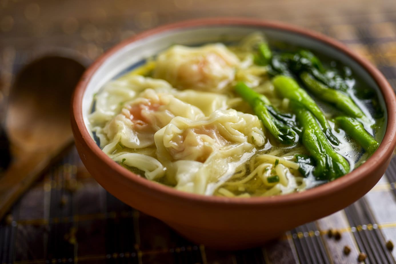 soupe wonton dans un bol orange avec des choy sum