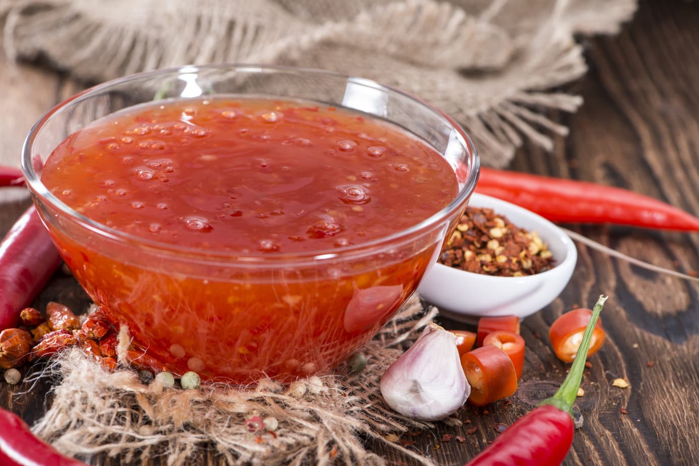 sauce sweet chili maison dans un bol sur fond de bois entourée de ses ingrédients