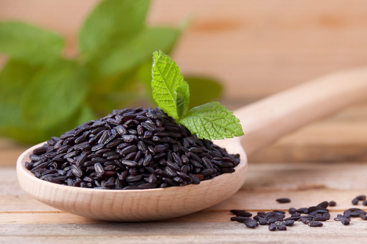 Arroz negro en una cuchara de madera sobre fondo de madera