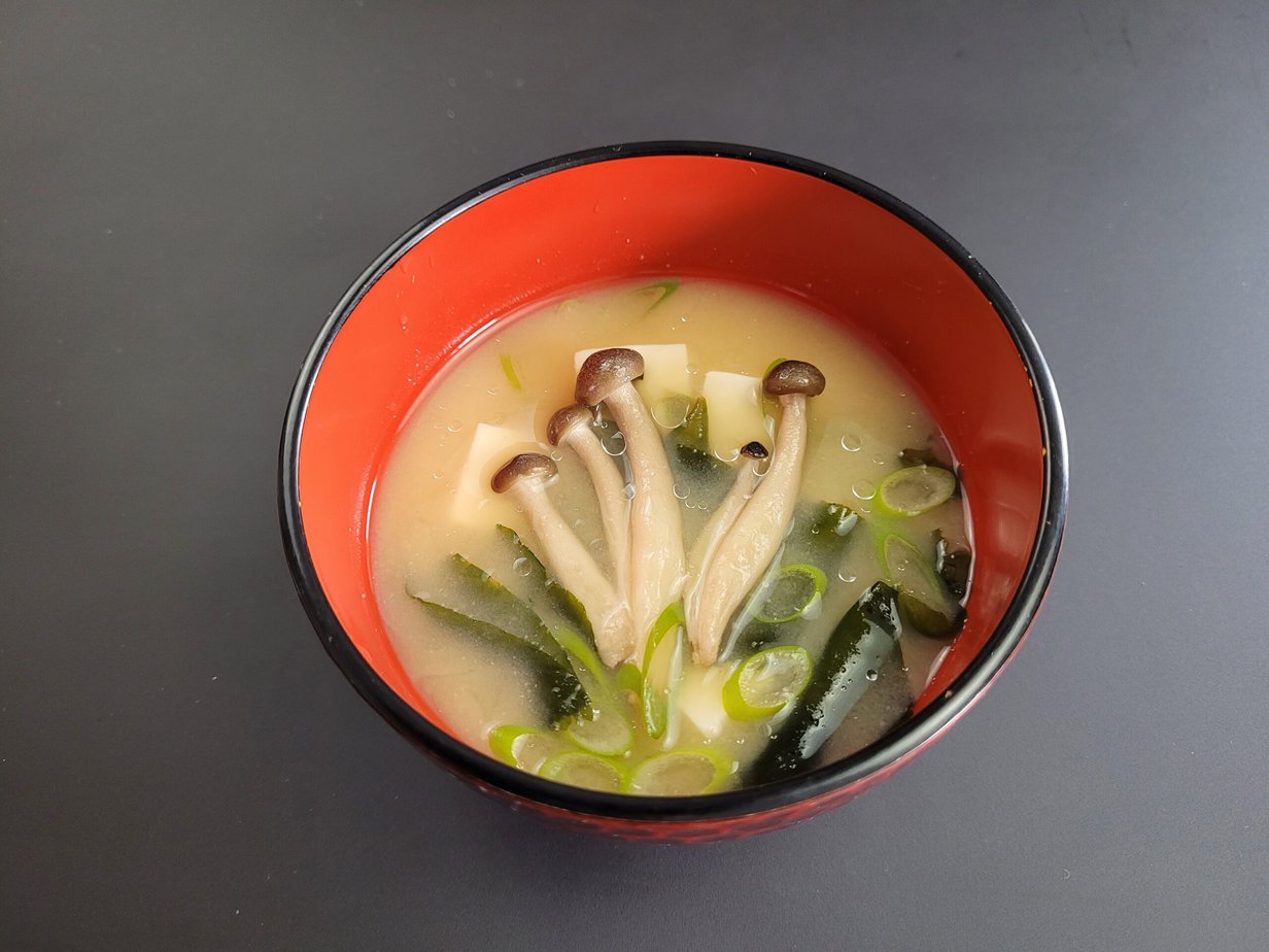 soupe à base de miso dans bol rouge sur fond sombre