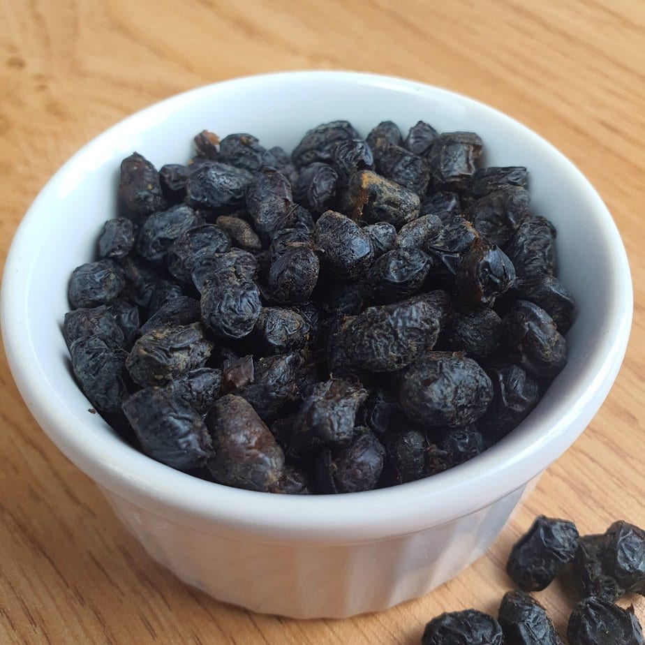 haricots noirs fermentés dans une verrine blanche sur fond e bois avec quelques grains à côté