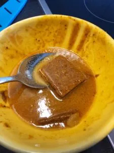 roux de curry japonais se dissolvant dans un bol jaune avec une cuillère en métal