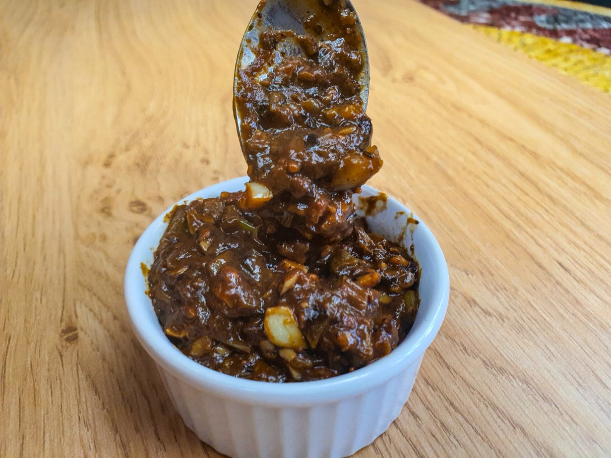 sauce aux haricots noir fermentés dans une verrine blanche avec une cuillère dedans et un fond de bois