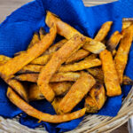 frites de patates douce dans un panier en osier avec une serviette bleue en papier