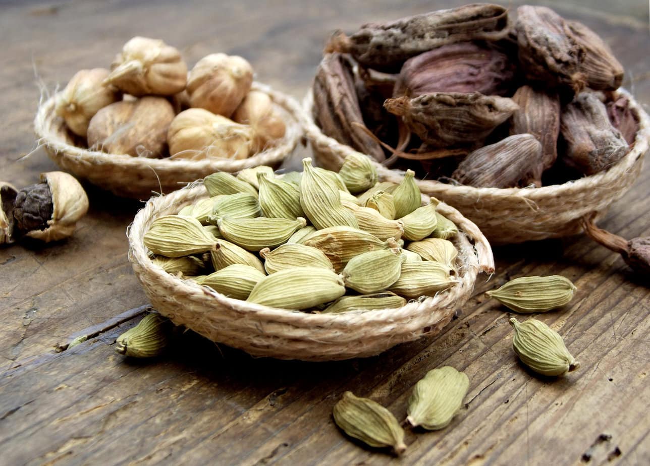 Plusieurs sortes de cardamome sur fond de bois
