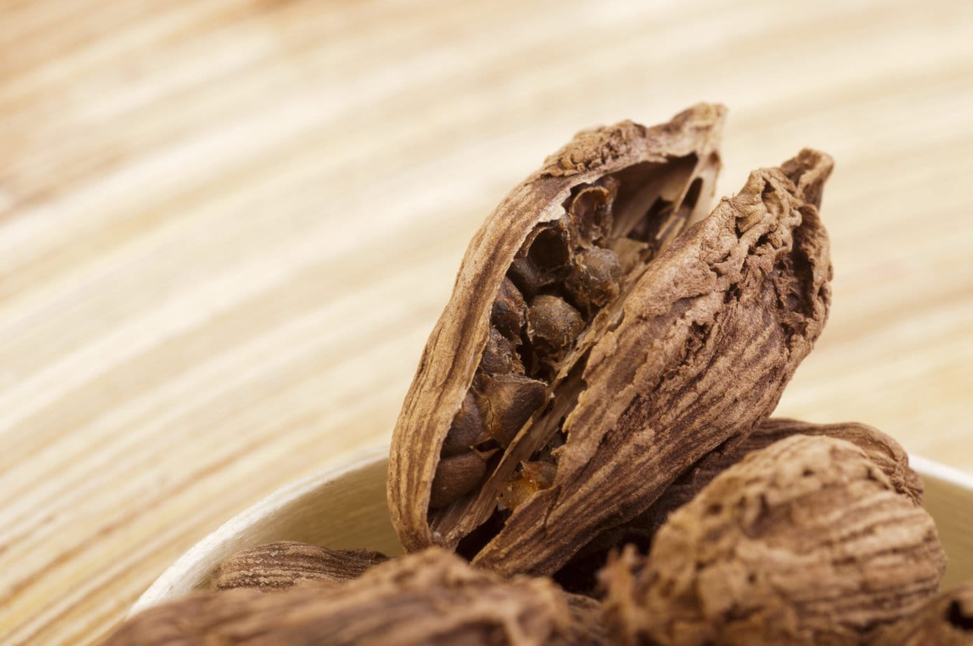 cardamome noire ouverte sur fond de bois