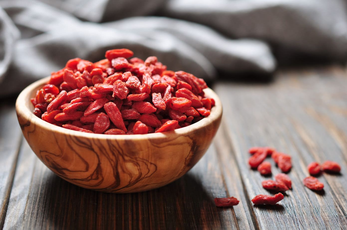 baies de goji séchées dans un bol en bois posé sur une table en bois