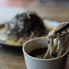 nouilles soba trempées dans la sauce tsuyu sur fond de bois