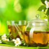 thé vert au jasmin dans une tasse et une théière sur une table en bois sur fond vert