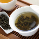 thé oolong infusé dans une tasse blanche posée sur une natte en bambou
