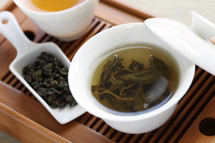 thé oolong infusé dans une tasse blanche posée sur une natte en bambou
