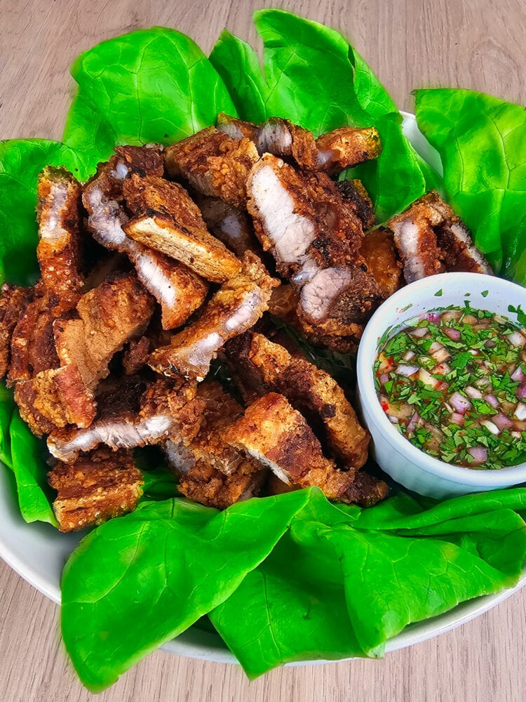 moo grob thaïlandais sur un lit de laitue avec une sauce à tremper