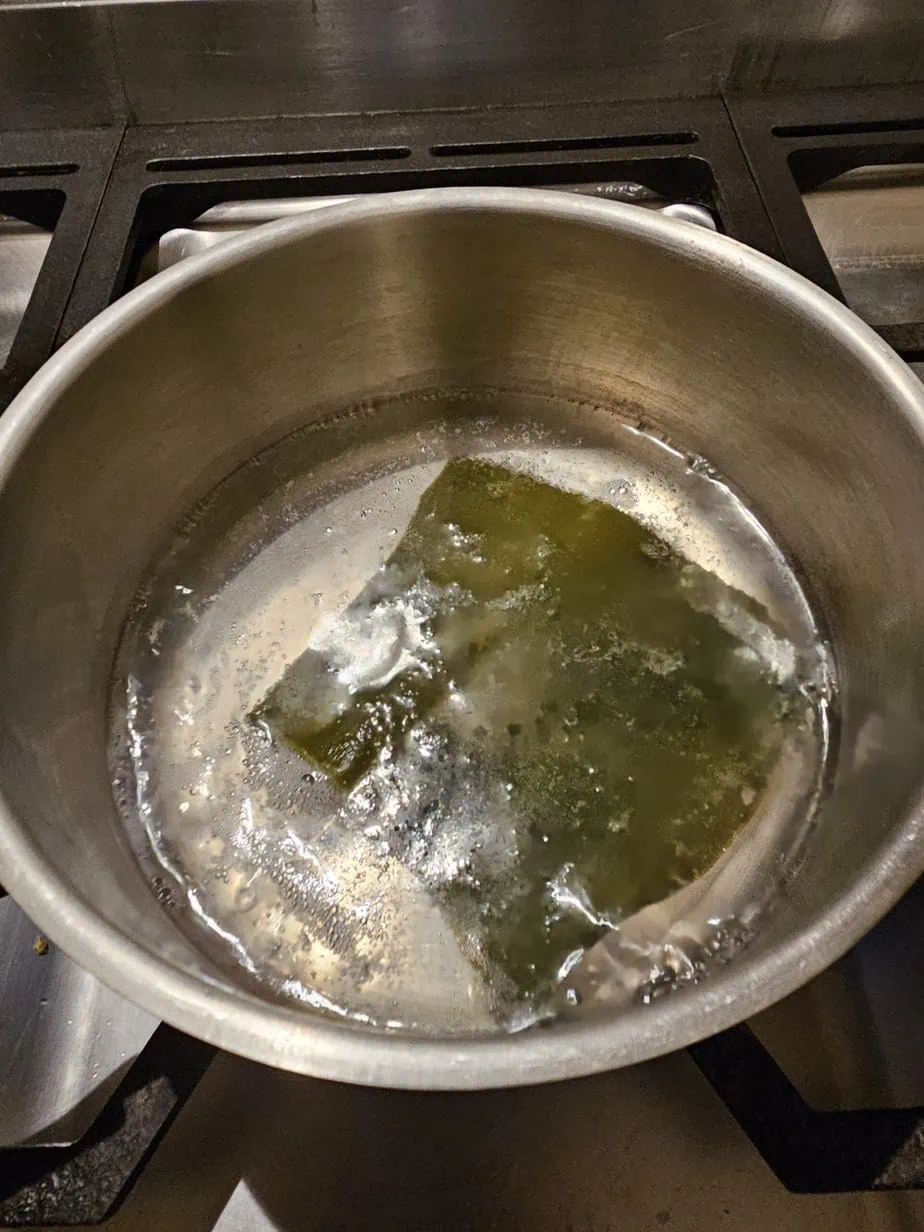 kombu dans de l'eau bouillante contenue dans une casserole en métal gris