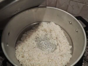 riz gluant lavé dans une passoire en métal