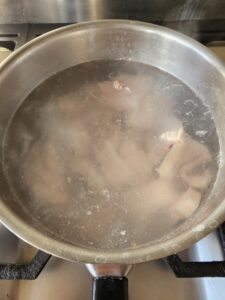 morceaux de lard dans une casserole en métal comportant de l'eau bouillante