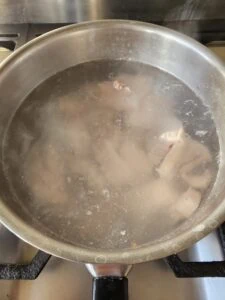 morceaux de lard dans une casserole en métal comportant de l'eau bouillante