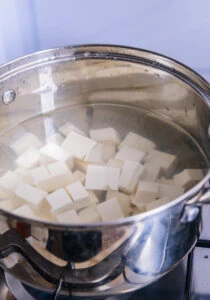 cubes de tofu qui blanchissent dans l'eau bouillante