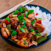 Plat de poulet kung pao sur du riz sur un fond de bois
