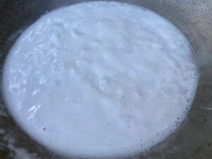 lait de coco dans un wok porté à ébullition