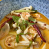 tom yum dans un bol avec un bouillon rouge pâle