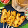 brochettes de poulet satay sur ardoise à côté de leur sauce à tremper aux cacahuètes