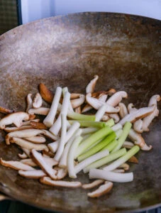 champignns et jeunes oignosn dans wok