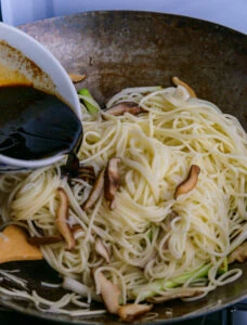sauce versée dans wok sur nouilles