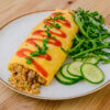 omurice sur une assiette blanche sur fond de bois