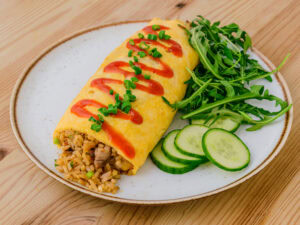 omurice sur une assiette blanche sur fond de bois