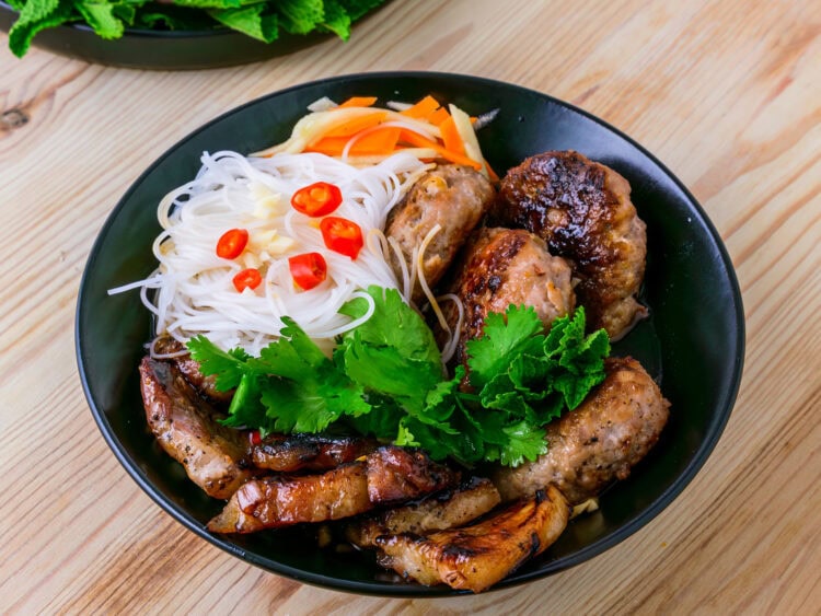 Bun cha dans un bol noir sur fond de bois