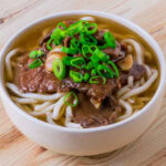 niku udon dans un bol blanc sur fond de bois