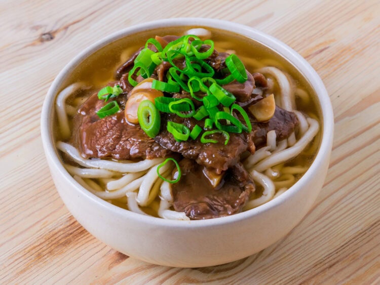 niku udon dans un bol blanc sur fond de bois