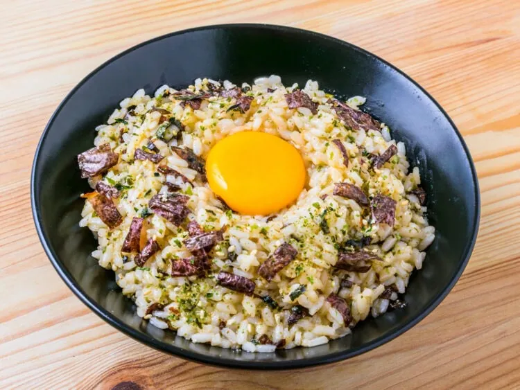 tamago kake gohan dans un bol noir sur fond de bois