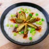 congee cantonaise dans un bol noir sur fond de bois