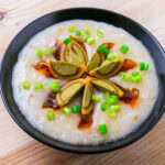 congee cantonaise dans un bol noir sur fond de bois