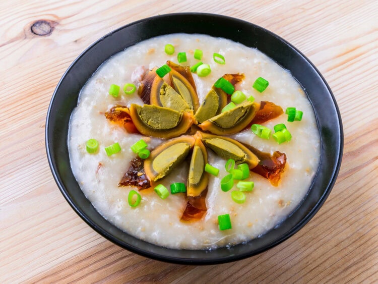 congee cantonaise dans un bol noir sur fond de bois