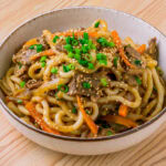 bulgogi udon dans un bol sur fond de bois