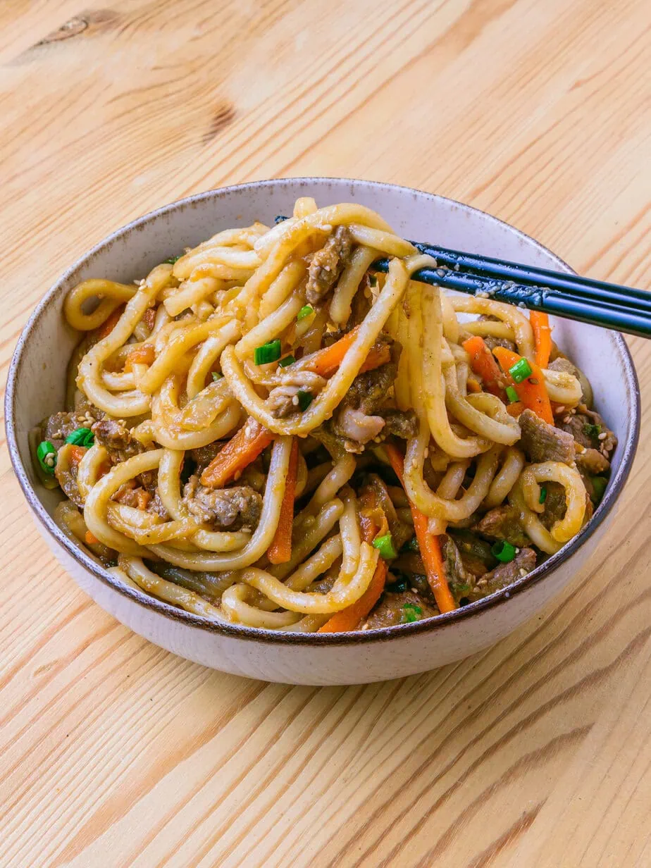 bulgogi udon sur fond de bois soulevé par des baguettes