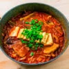 kimchi jjigae dans un bol sur fond de bois