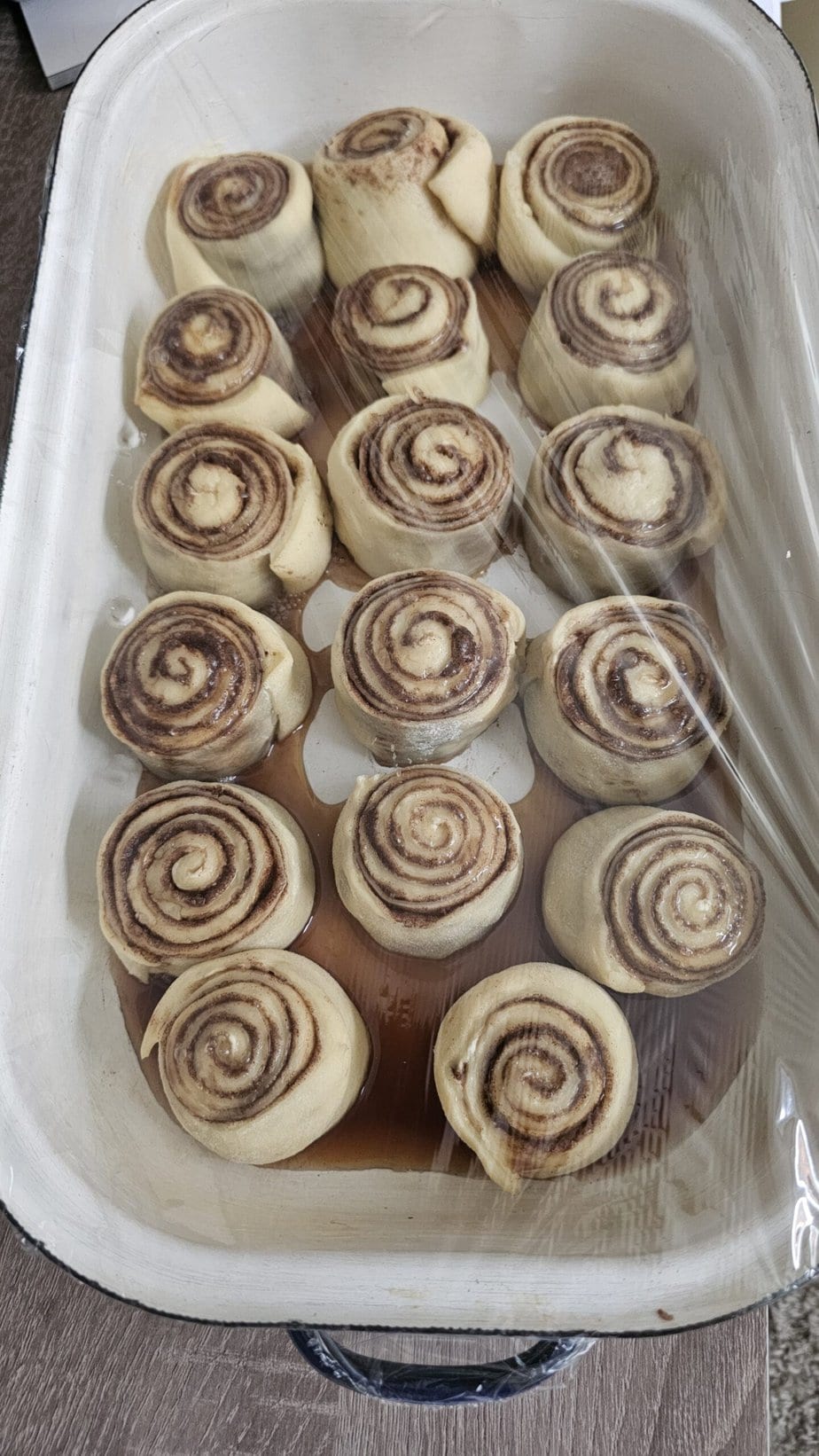 cinnamon rolls dans un plat pour four blanc sous cellophane
