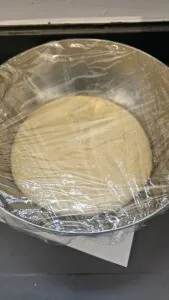 pâte pour cinnamon rolls dans un bol sous cellophane en train de lever