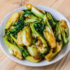 pak choi sauté dans une assiette blanche sur fond de bois