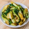 pak choi sauté dans une assiette blanche sur fond de bois