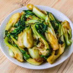 pak choi sauté dans une assiette blanche sur fond de bois
